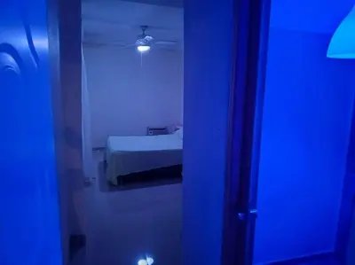 a room with a bedroom with a bed and a blue light at Acogedor apartamento entero in Mandinga