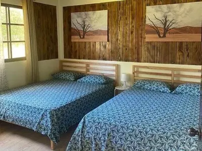 two beds in a bedroom with wooden walls at Villa las Rosas JP in Bayaguana