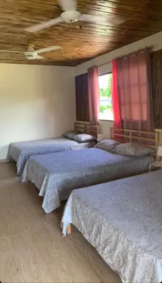 three beds in a room with a ceiling at Villa las Rosas JP in Bayaguana