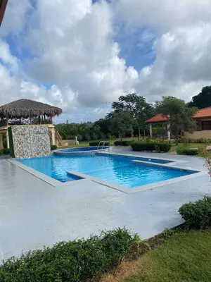 a large swimming pool with blue water in a yard at Villa las Rosas JP in Bayaguana