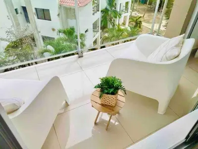 a living room with a white chair and a potted plant at Boca chica Apartment Near the bech in Boca Chica