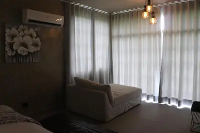 a bedroom with a chair and a window with curtains at Villa Cantares del Rio in La Cuaba