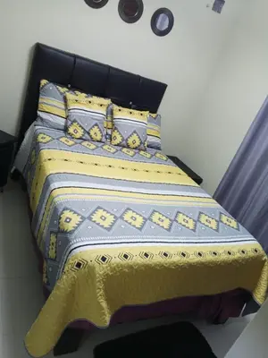 a bedroom with a bed with a yellow and blue comforter at Hermoso apartamento in Santo Domingo