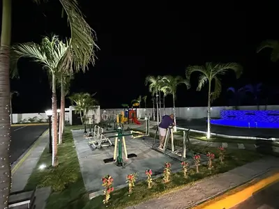 a person on a playground at night with palm trees at RESIDENCIAL LEGADo in Azua de Compostela