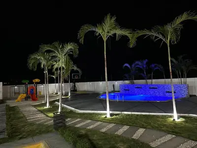 a park at night with palm trees and a blue bench at RESIDENCIAL LEGADo in Azua de Compostela