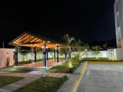 a pavilion at night with palm trees and a building at RESIDENCIAL LEGADo in Azua de Compostela