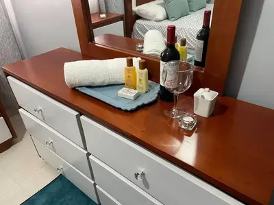 a wooden dresser with bottles of wine and a glass at apartamento 3 habitaciones 15 minutos aeropuerto las america in San Isidro