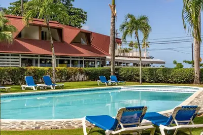 a swimming pool with blue chairs and a building at Renovated Condo at the Beach Close to Everything in Las Terrenas