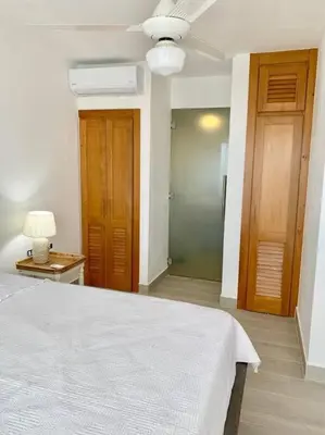 a bedroom with a white bed and wooden doors at Gorgeous 2 bedroom apartment in Vibe Residence in Bayahibe
