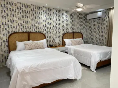 a bedroom with two beds with white sheets at Sun on the bay beach hotel in Palmar de Ocoa