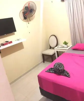 a bedroom with a pink bed and a chair at Confortable Apto de relajación in Los Paredones