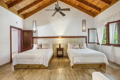 two beds in a bedroom with a ceiling fan at Casa de Campo villa – Luxurious villa up to 12 people with pool jacuzzi golf in La Romana