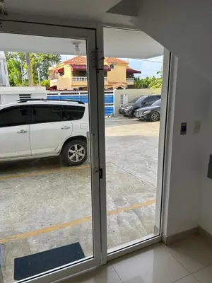 a white van parked in a parking lot through a sliding glass door at Samana Complexes Los Robles VII in Los Paredones