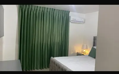 a bedroom with a green curtain and a bed at Residencial Mediterraneo in Santiago de los Caballeros