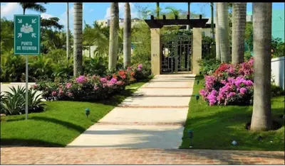 a walkway in a park with flowers and a sign at Residencial Mediterraneo in Santiago de los Caballeros