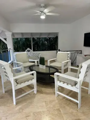 a living room with white chairs and a table at VILLA EN CASA DE CAMPO, La Romana, Rep Dom in La Romana
