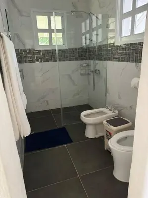 a bathroom with two toilets and a glass shower at VILLA EN CASA DE CAMPO, La Romana, Rep Dom in La Romana