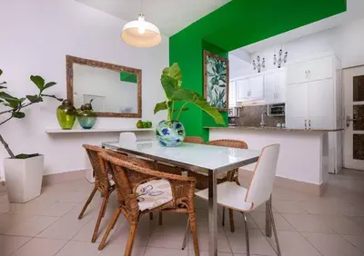 a dining room with a table and chairs and a green wall at Las Terrenas Haven in Las Terrenas