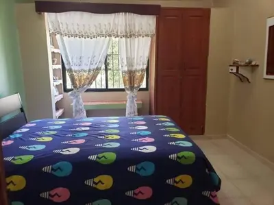 a bedroom with a bed with a blue comforter and a window at Home away from Home in La Villa Isabela in La Isabela