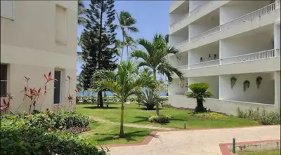 a large apartment building with palm trees and a yard at Albatros by R&R in Villas del Mar