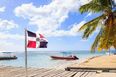 a flag on a beach with two boats in the water at Apto CGM Esmeralda in Bayahibe