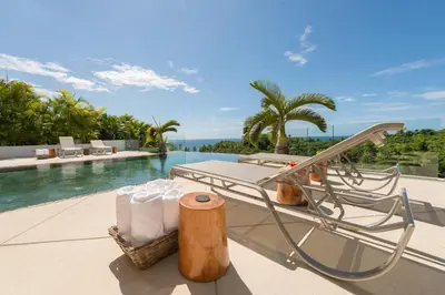 a resort pool with a table and chairs on a patio at Casa Phil - Amazing Sea View Luxury Modern, Fully Staffed in Las Terrenas