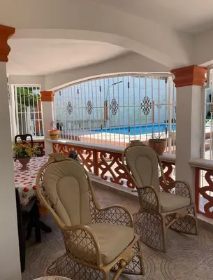 a room with chairs and a balcony with a pool at Villa Fiordalisa in San Felipe de Puerto Plata