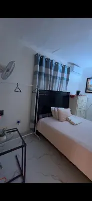 a bedroom with a bed with a black headboard and curtains at Fantástico con luz aire tv y cocina in La Romana