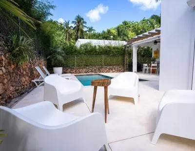 a patio with white chairs and a table and a pool at Chameleon Village in El Limón