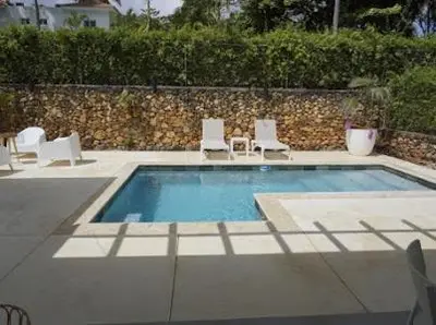 a swimming pool with two lawn chairs at Chameleon Village in El Limón