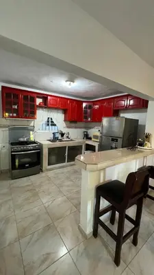 a large kitchen with red cabinets and a chair in it at Céntrico con wifi, luz,gas, TV y aire incluido in La Romana