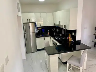 a kitchen with white cabinets and a black counter top at D&L Apartment in Bayahibe