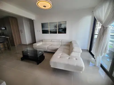 a living room with a white couch and a table at Cama king, piscina 3 habitacines in Santiago de los Caballeros