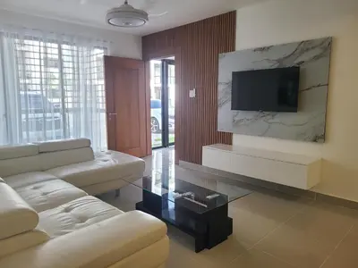 a living room with a couch and a flat screen tv at Cama king, piscina 3 habitacines in Santiago de los Caballeros
