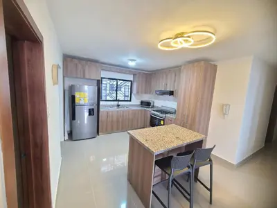 a kitchen with a table and two chairs and a refrigerator at Cama king, piscina 3 habitacines in Santiago de los Caballeros