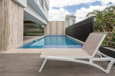 a white chair sitting next to a swimming pool at Encantador Apto en Torre de Lujo, Piscina, AC & Parking in Santo Domingo