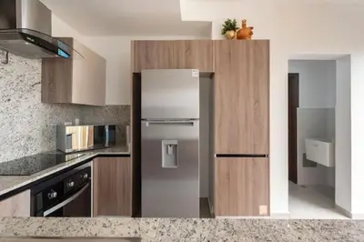 a kitchen with a stainless steel refrigerator and wooden cabinets at Encantador Apto en Torre de Lujo, Piscina, AC & Parking in Santo Domingo