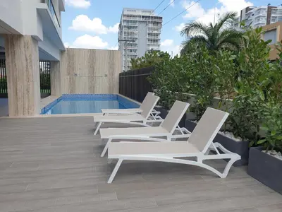 a row of white lounge chairs next to a pool at Encantador Apto en Torre de Lujo, Piscina, AC & Parking in Santo Domingo