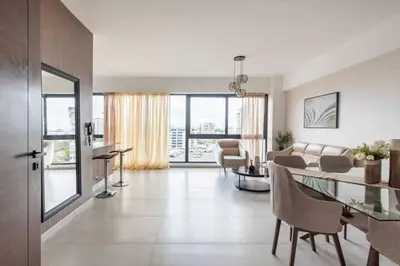 a living room with a table and chairs and a living room at Encantador Apto en Torre de Lujo, Piscina, AC & Parking in Santo Domingo