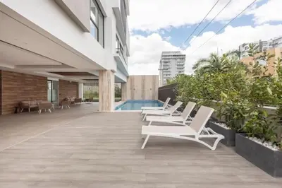 a row of white lounge chairs sitting on a patio at Encantador Apto en Torre de Lujo, Piscina, AC & Parking in Santo Domingo