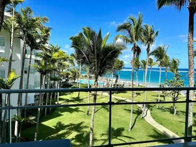 a view of the beach and palm trees from a balcony at Luxury 1 Bedroom with Seaview Seawinds in Cabarete