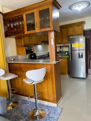 a kitchen with wooden cabinets and a white bar stool at Hogar lejos de casa, piscina in San Cristóbal