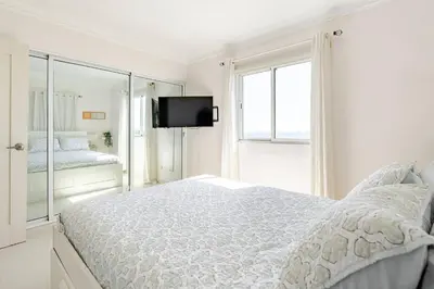 a white bedroom with a large bed and a tv at Luxury Ocean View Condo in Santo Domingo in La Francia