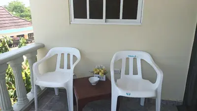 two white chairs sitting next to a table on a balcony at Habitación Taina in Jarabacoa