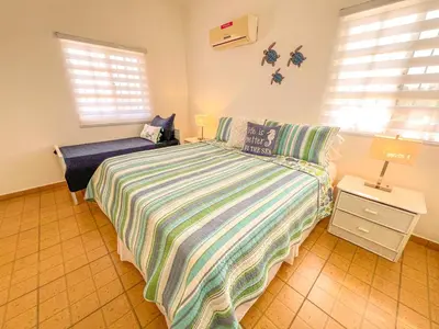 a bedroom with a bed and a nightstand and windows at Villa Cruz in Las Galeras