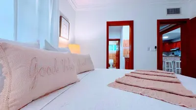 a white bed with two pink pillows on it at Walk to Beach, Shops, Dining, Pool View, Fast Wifi in Punta Cana