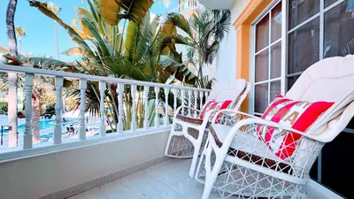 a balcony with two chairs and a view of the pool at Walk to Beach, Shops, Dining, Pool View, Fast Wifi in Punta Cana