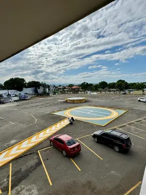 a parking lot with two cars and a basketball court at lovera hotel in Santiago de los Caballeros