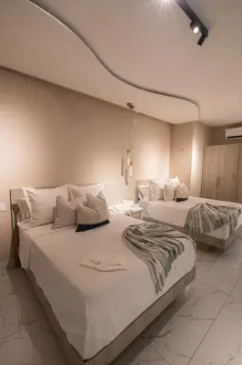 two beds in a room with white walls at lovera hotel in Santiago de los Caballeros