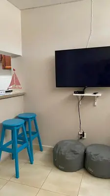 a living room with two blue stools and a flat screen tv at Apartamento en Proyecto Frente al Mar en Sosua in Los Altos de Jalisco